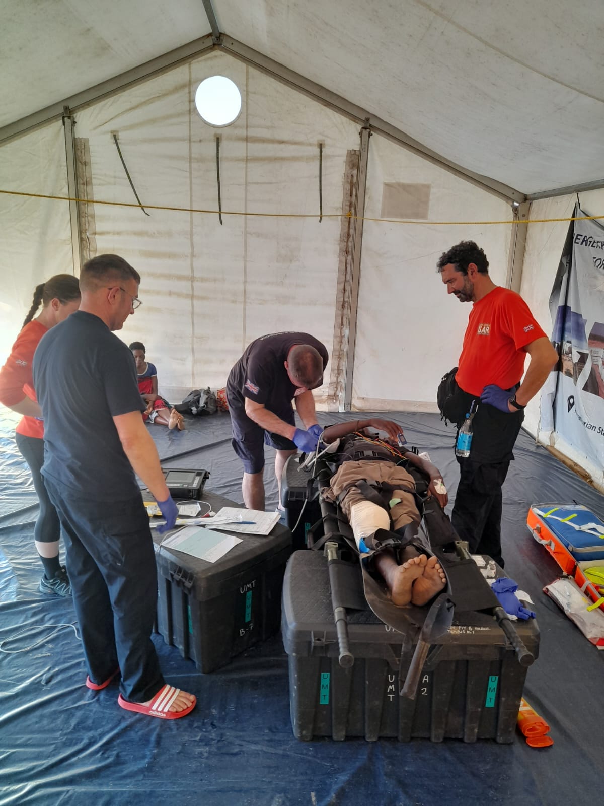 Rescue team treating a casualty on a stretcher in a field medical tent