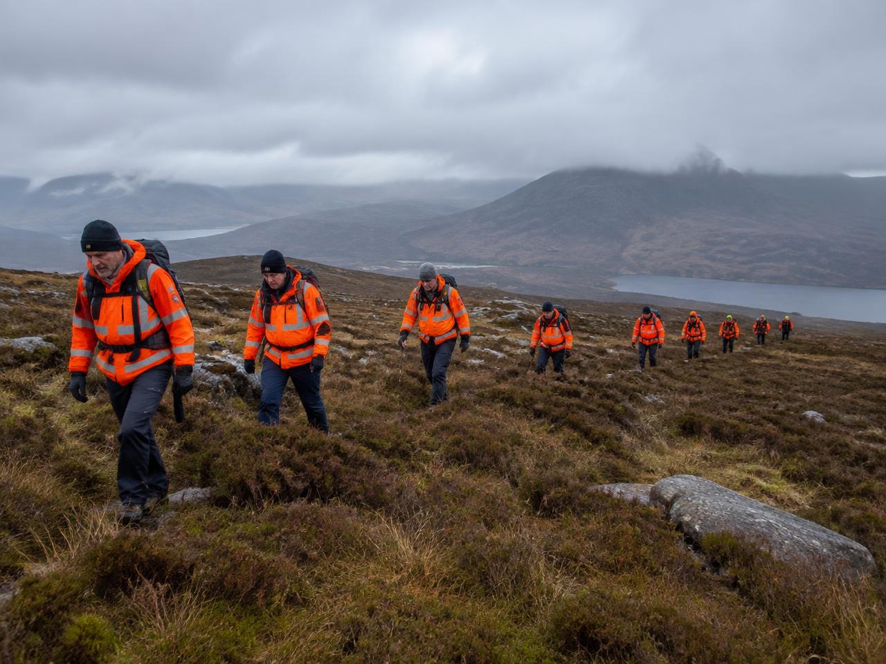 Search and rescue volunteers line-searching across open moorland terrain